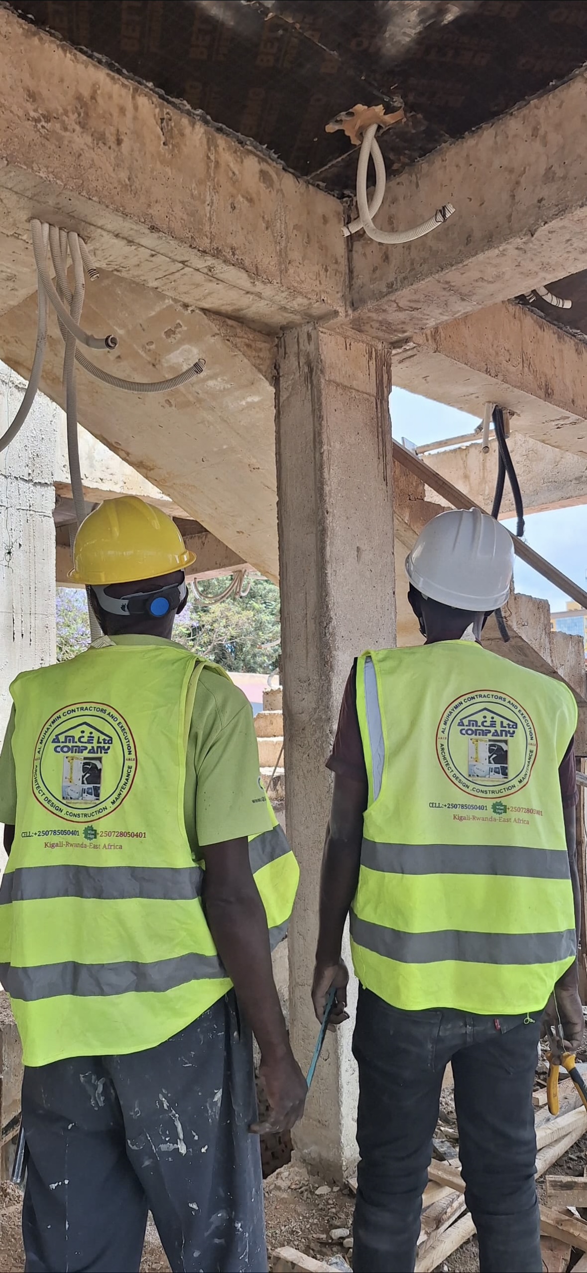 Two AMCE workers checking electrical conduit under a concrete slab