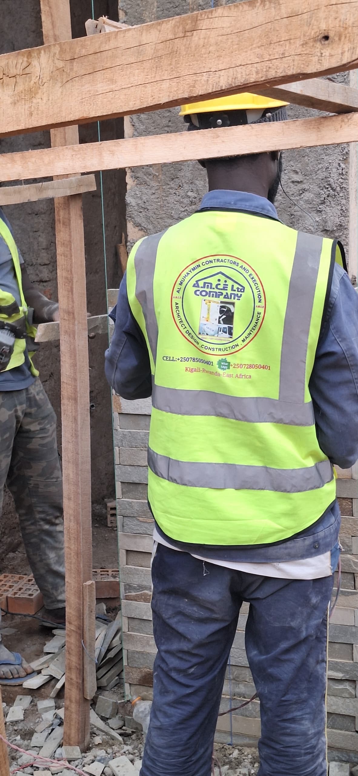 Close view of AMCE worker against a brick wall under construction