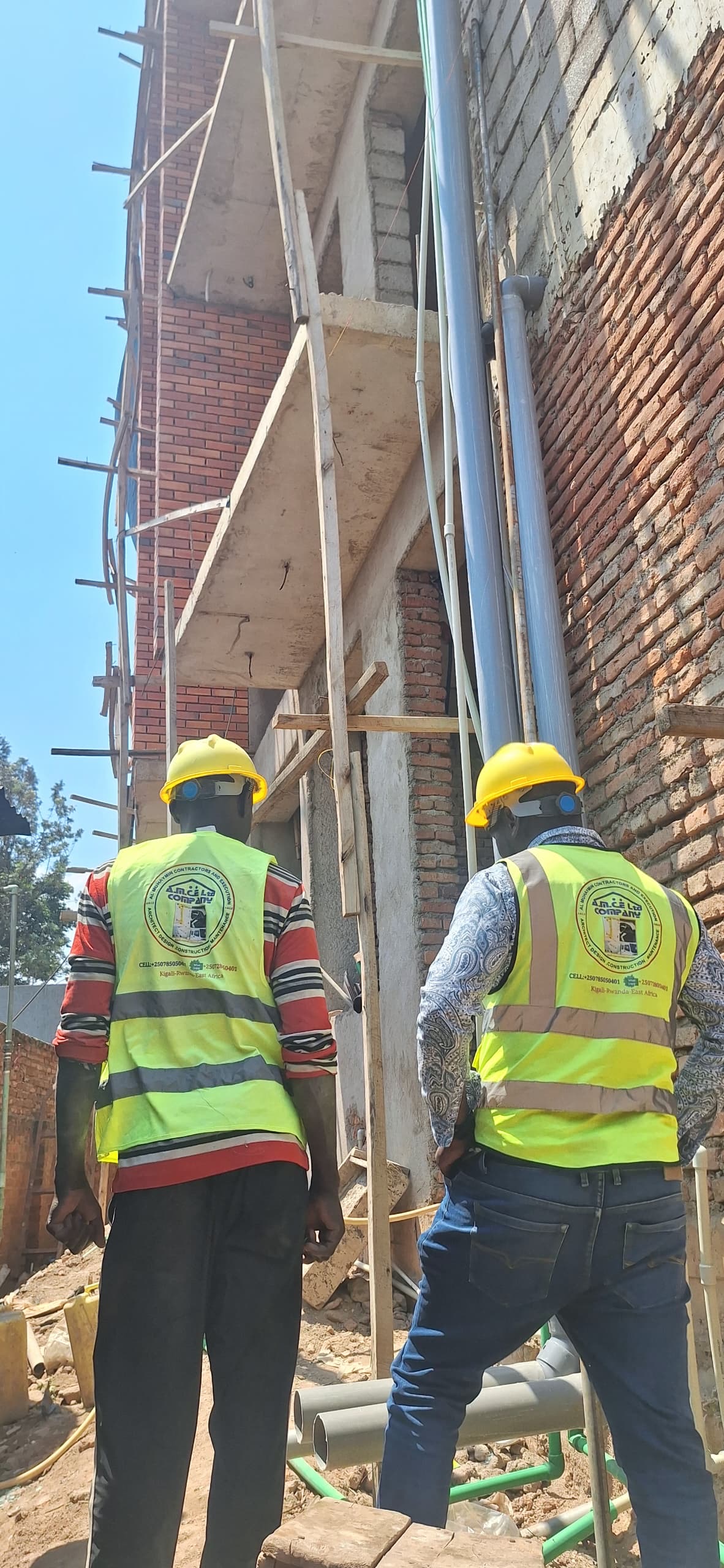 Two AMCE supervisors reviewing a scaffolded brick building